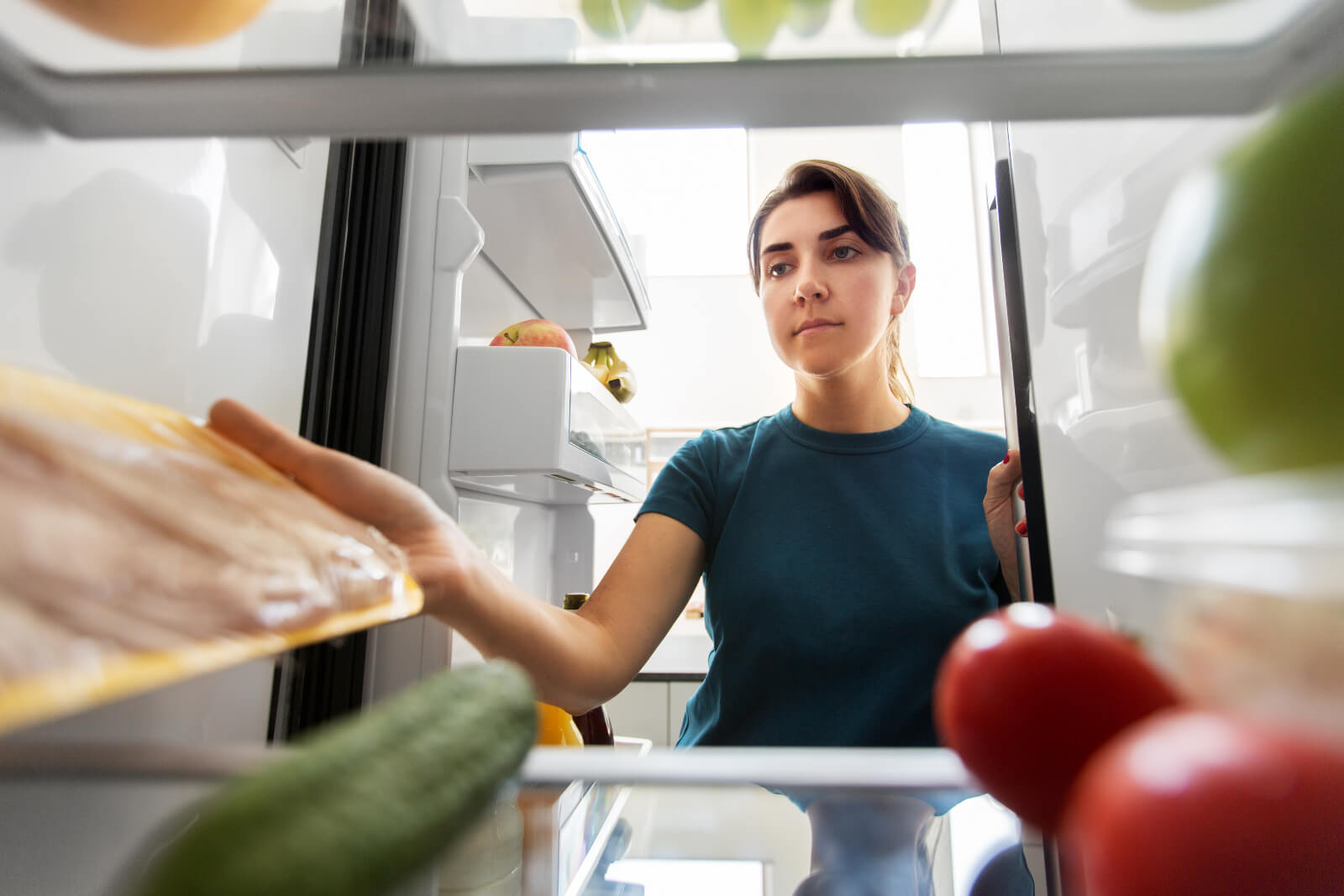 Woman grabbing some food from a refrigerator to illustrate 6 Month diet before weight loss surgery
